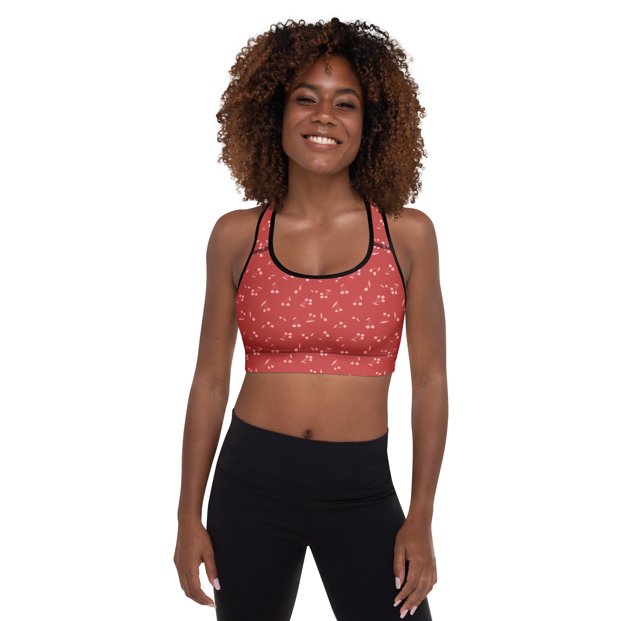 Pink cherry-print padded sports bra with black trim featuring buttery soft fabric and quick-dry support for women
