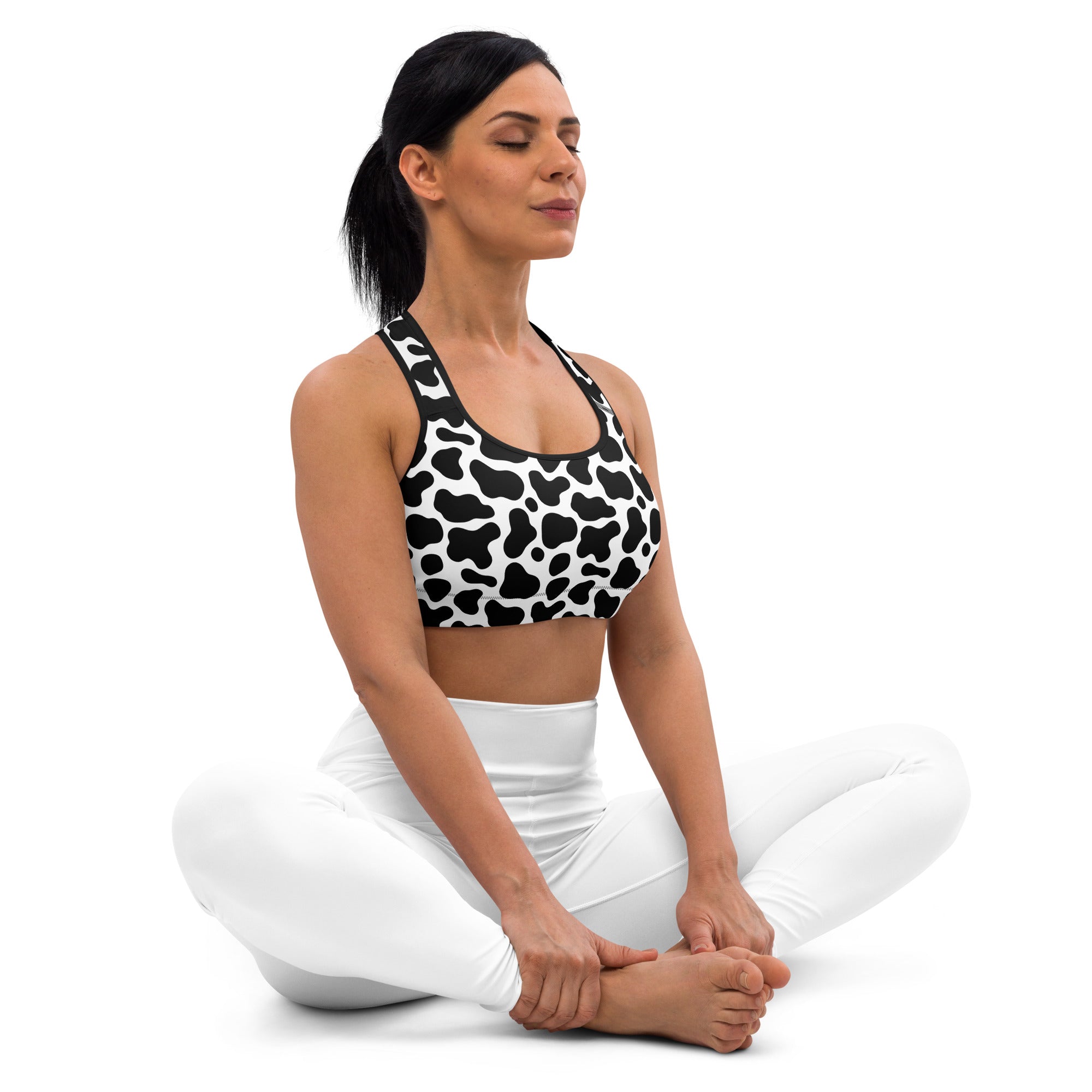 Women’s black and white cow print padded sports bra with buttery soft quick-dry fabric and racerback straps shown from back