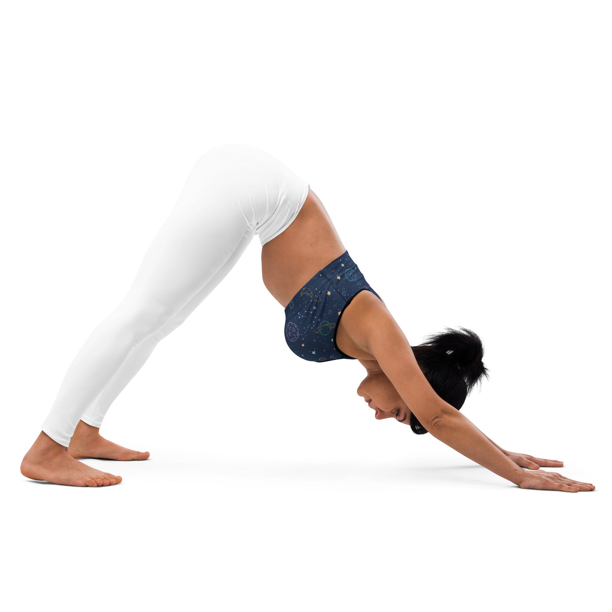 Woman wearing white leggings and a dark blue star-patterned colorful galaxy space padded sports bra is buttery soft supportive and quick-dry