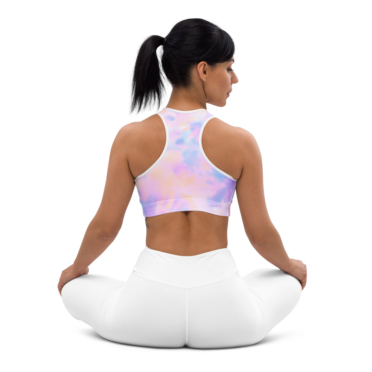 A woman wearing a pastel tie-dye women’s watercolor padded sports bra with white trim and matching quick-dry leggings