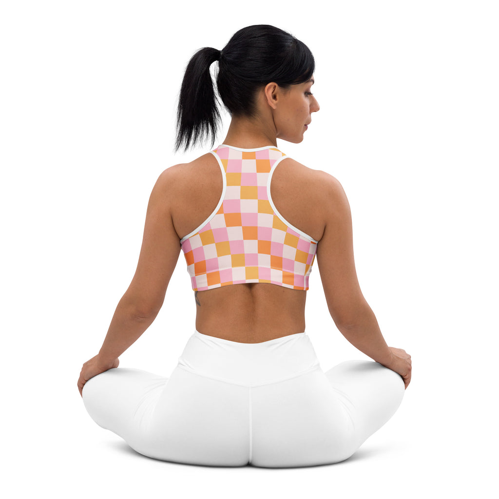 A woman wearing a women’s pink and orange checkerboard padded sports bra with white trim buttery soft and supportive