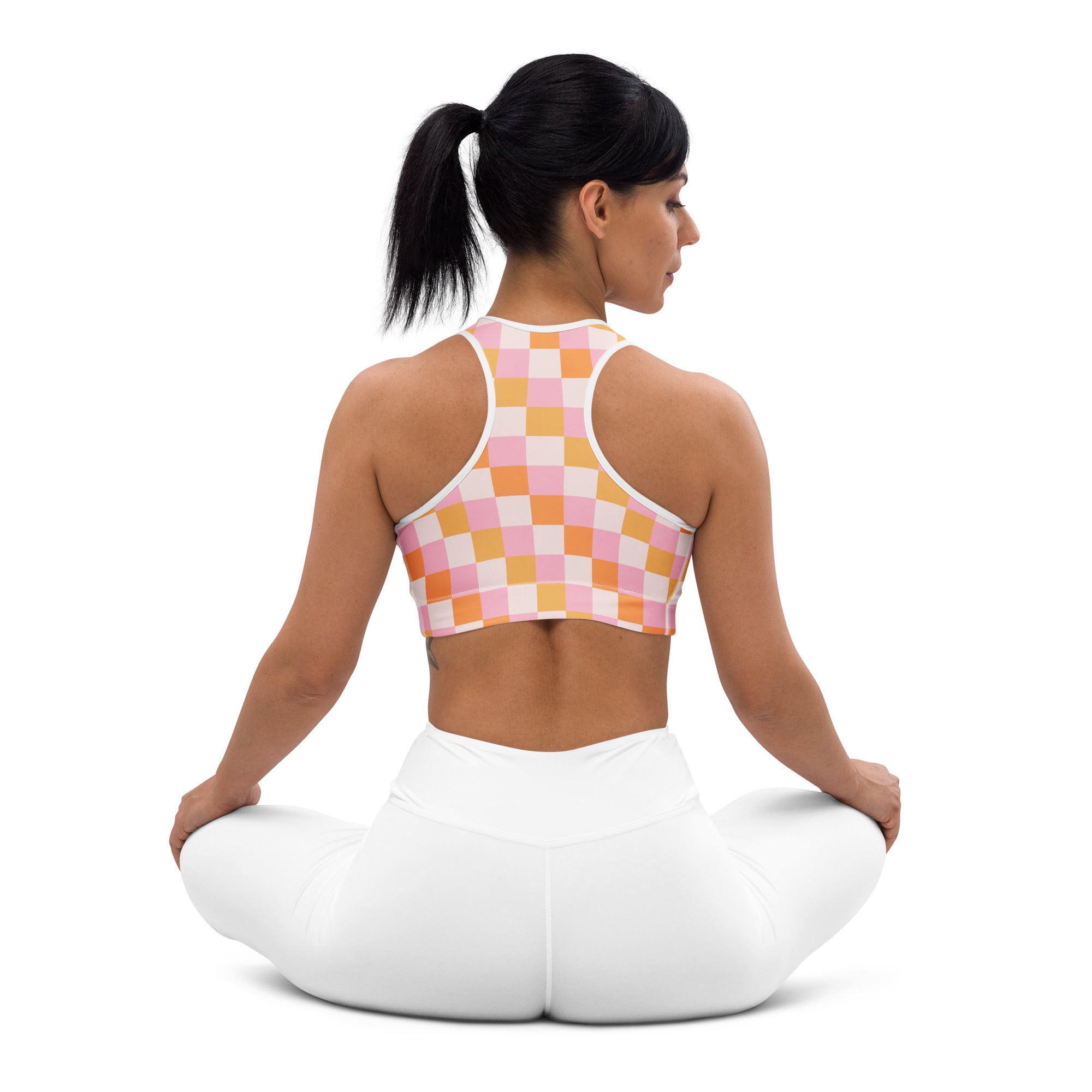 A woman wearing a women’s pink and orange checkerboard padded sports bra with white trim buttery soft and supportive