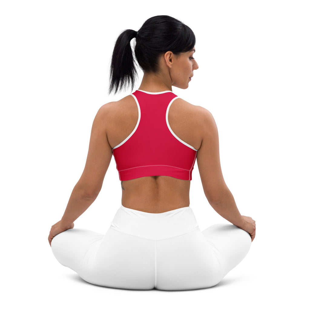 A woman wearing a vibrant crimson red padded sports bra with white trim and quick-dry leggings in a yoga pose
