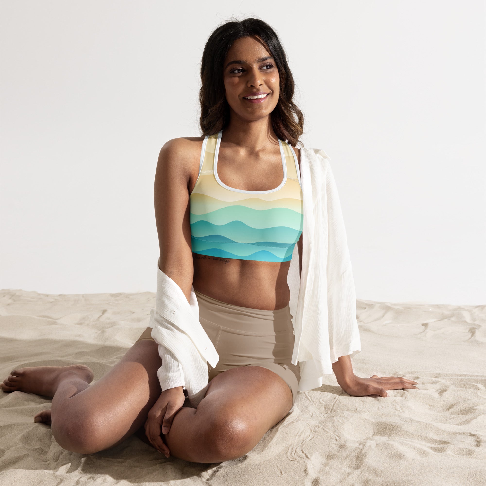 A woman wearing a women’s pastel ocean wave padded sports bra in buttery soft quick-dry yellow and blue hues