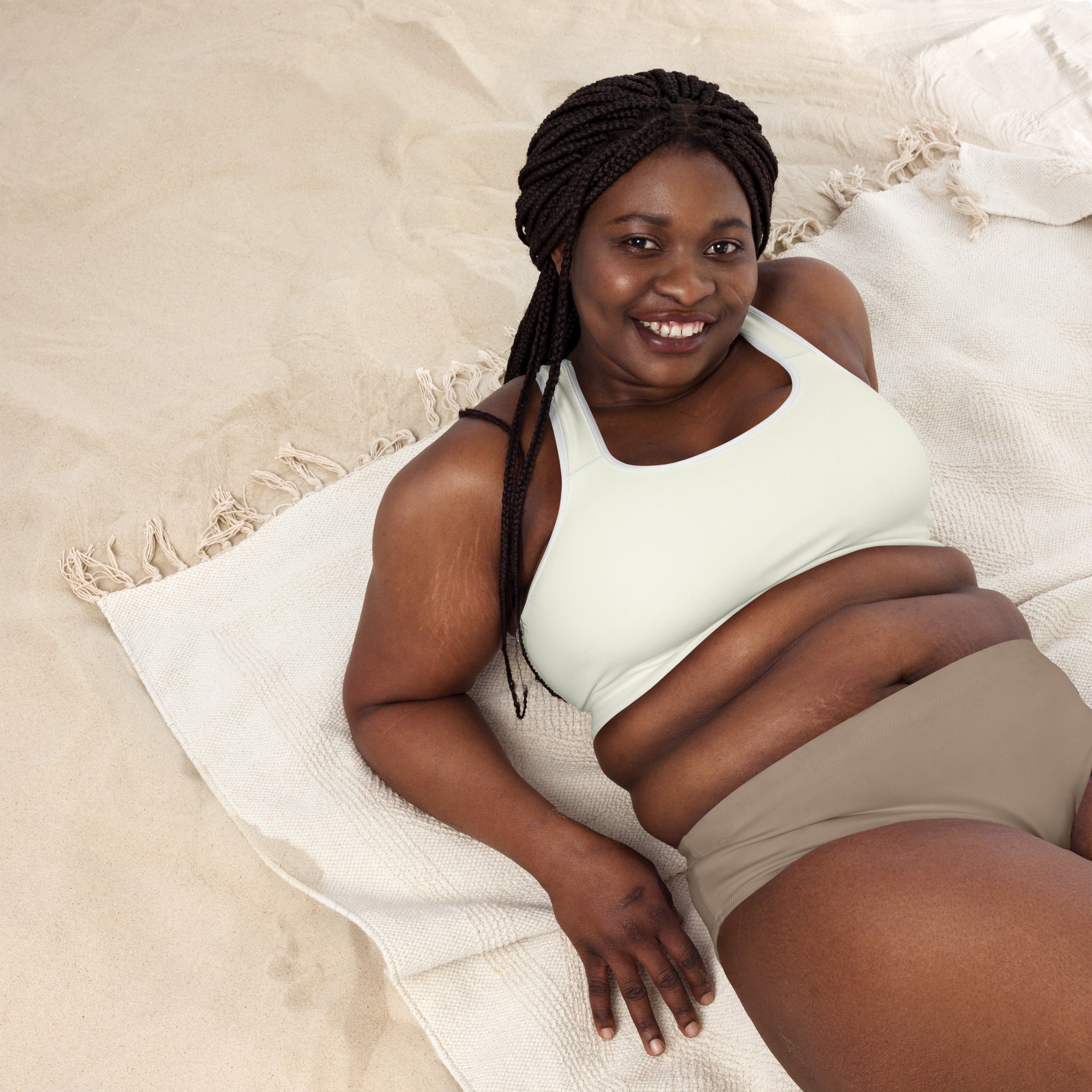 A woman lying on a white towel wearing a women’s cream padded sports bra in buttery soft quick-dry fabric
