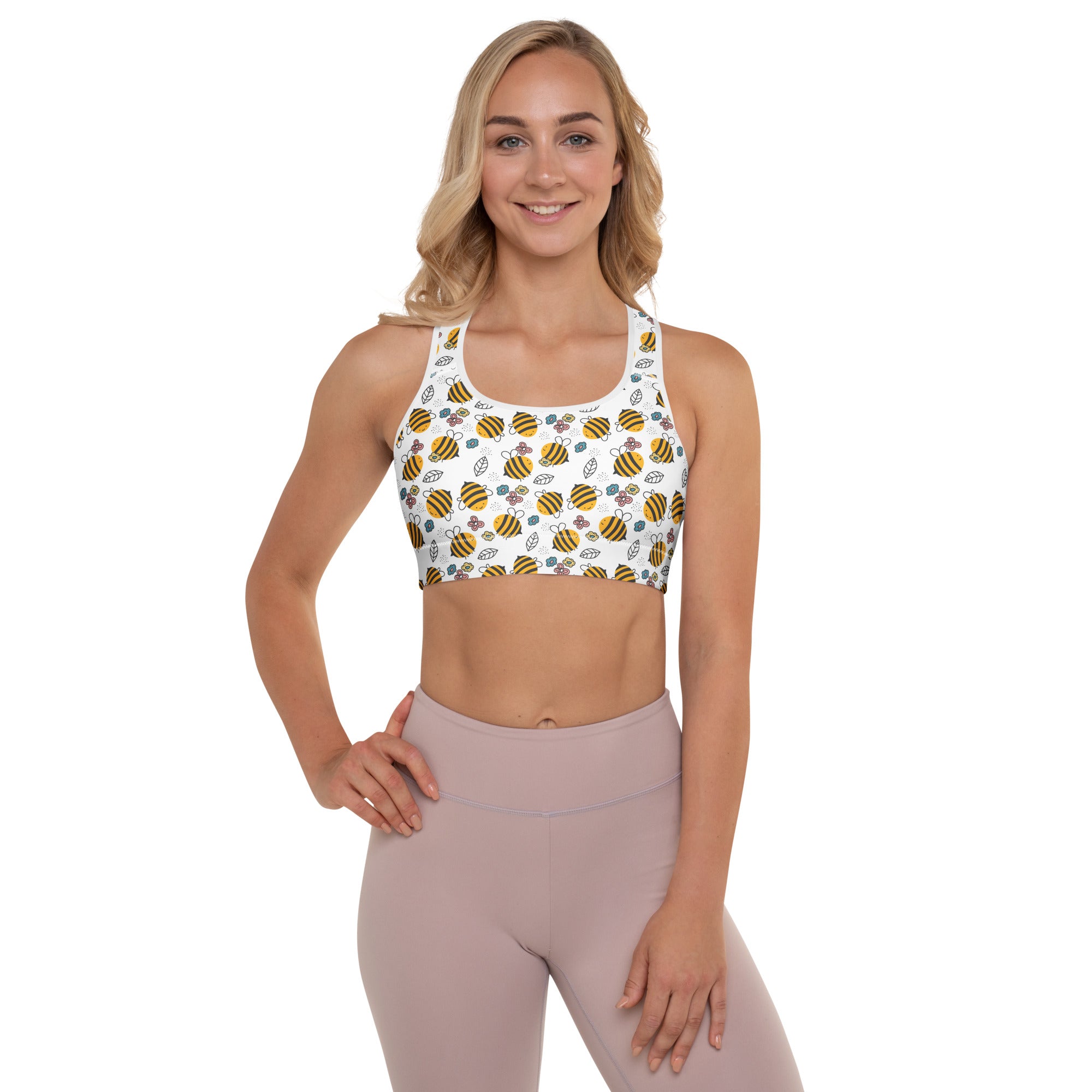 Woman wearing a sports bra with bee pattern and leggings on a white background