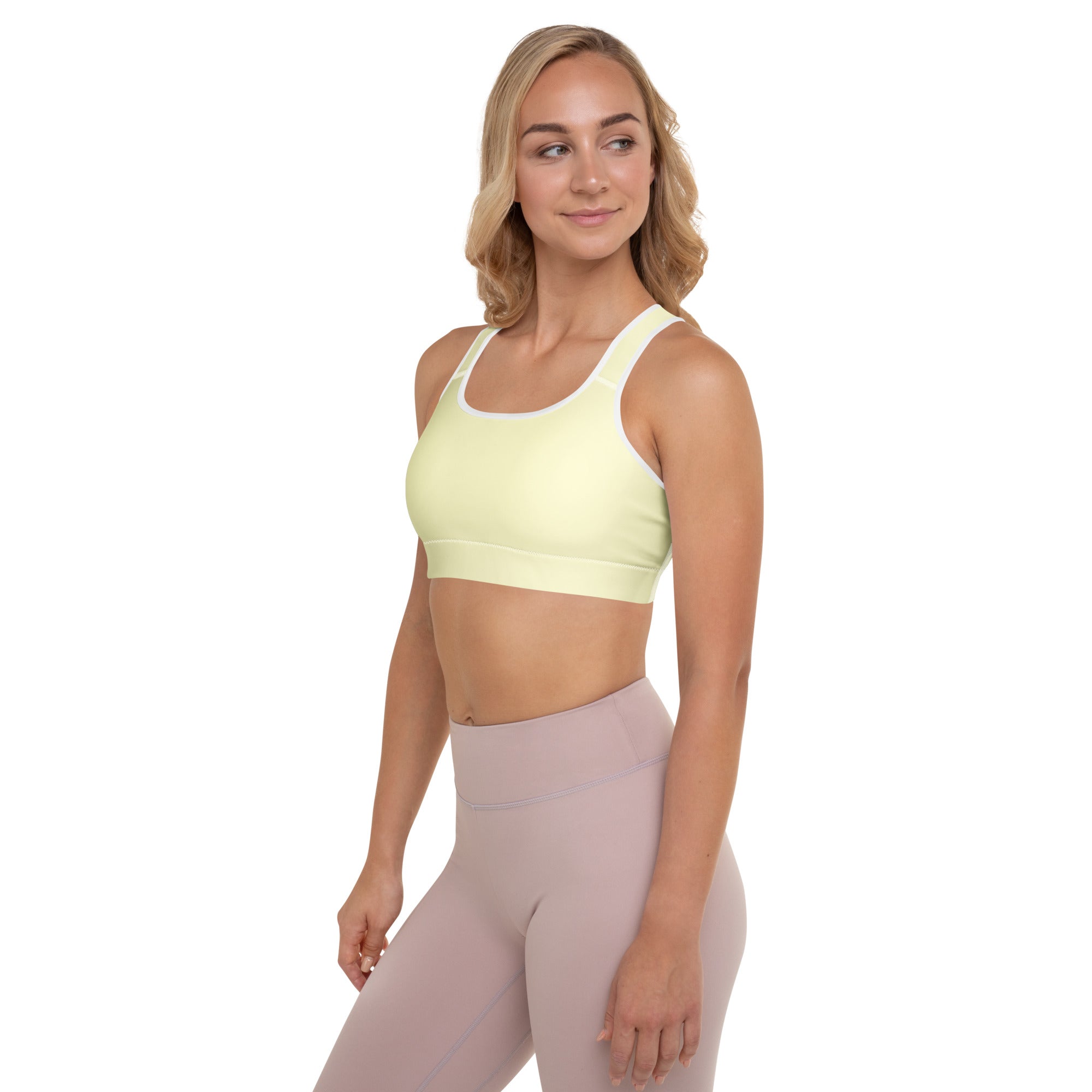 A pale yellow padded sports bra with white trim and adjustable straps made for quick-dry support