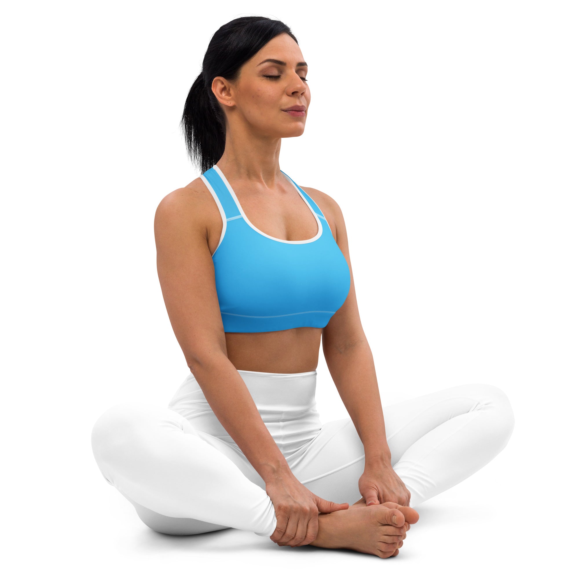 A woman wearing a women’s sky blue padded sports bra with white trim and matching white quick-dry leggings