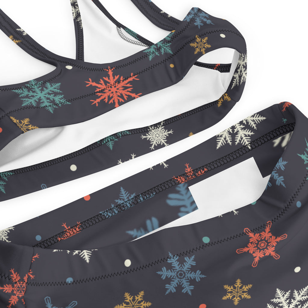 Black sports bra with colorful orange teal white and gold snowflake pattern made from quick drying recycled fabric with upf 50+