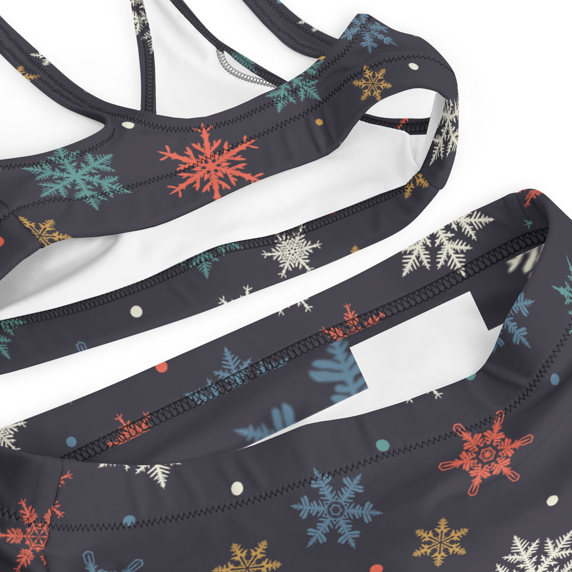 Black sports bra with colorful orange teal white and gold snowflake pattern made from quick drying recycled fabric with upf 50+