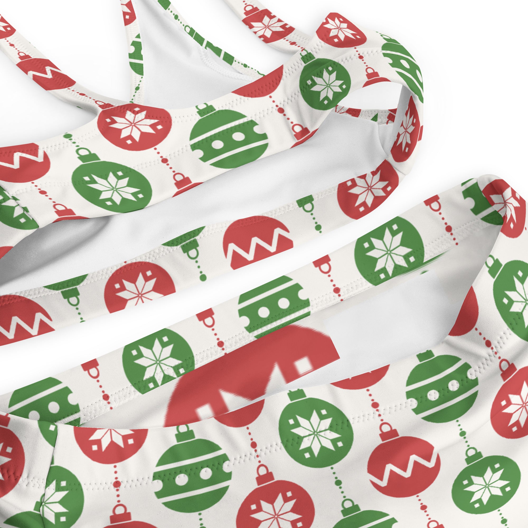 White bikini top with festive red and green christmas ornament pattern and snowflakes made from quick drying recycled fabric with upf 50+