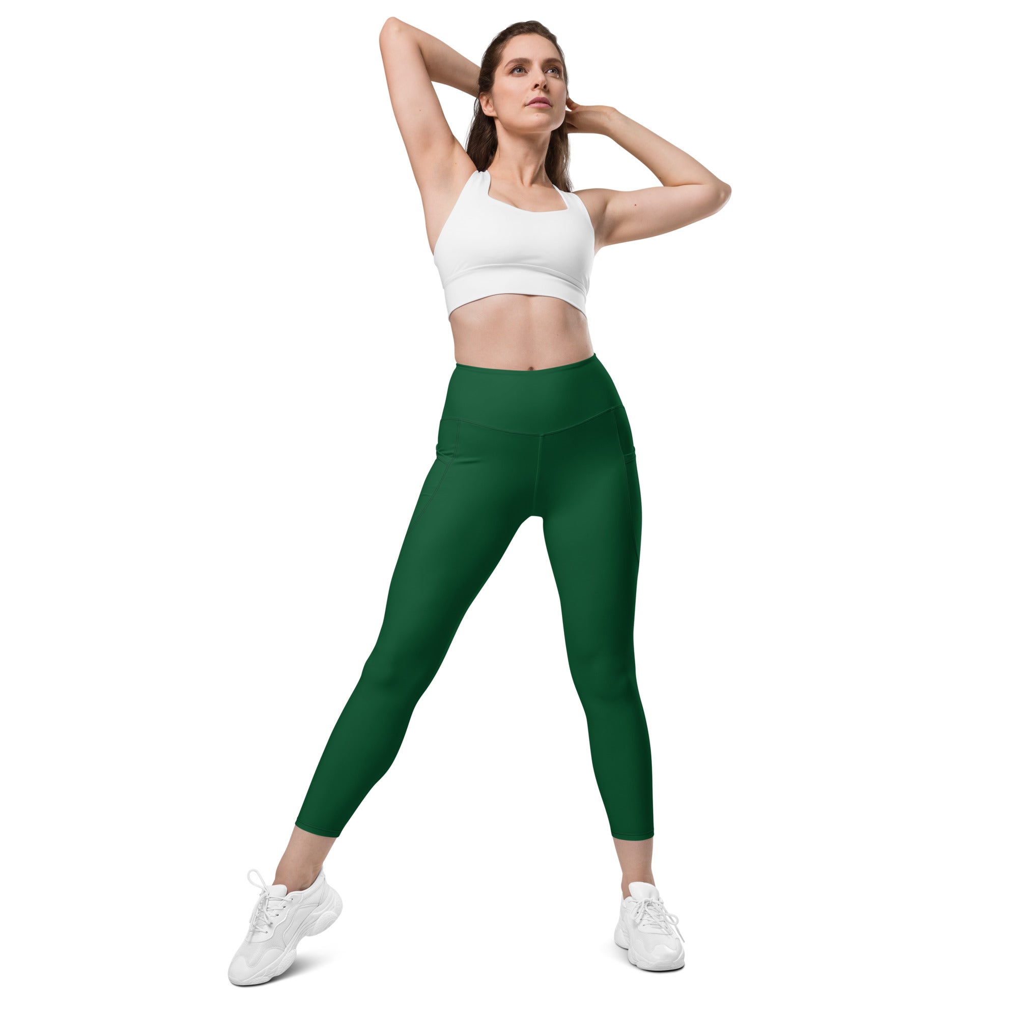 A pair of form-fitting forest green high-waisted yoga leggings with pockets made from stretchy athletic fabric