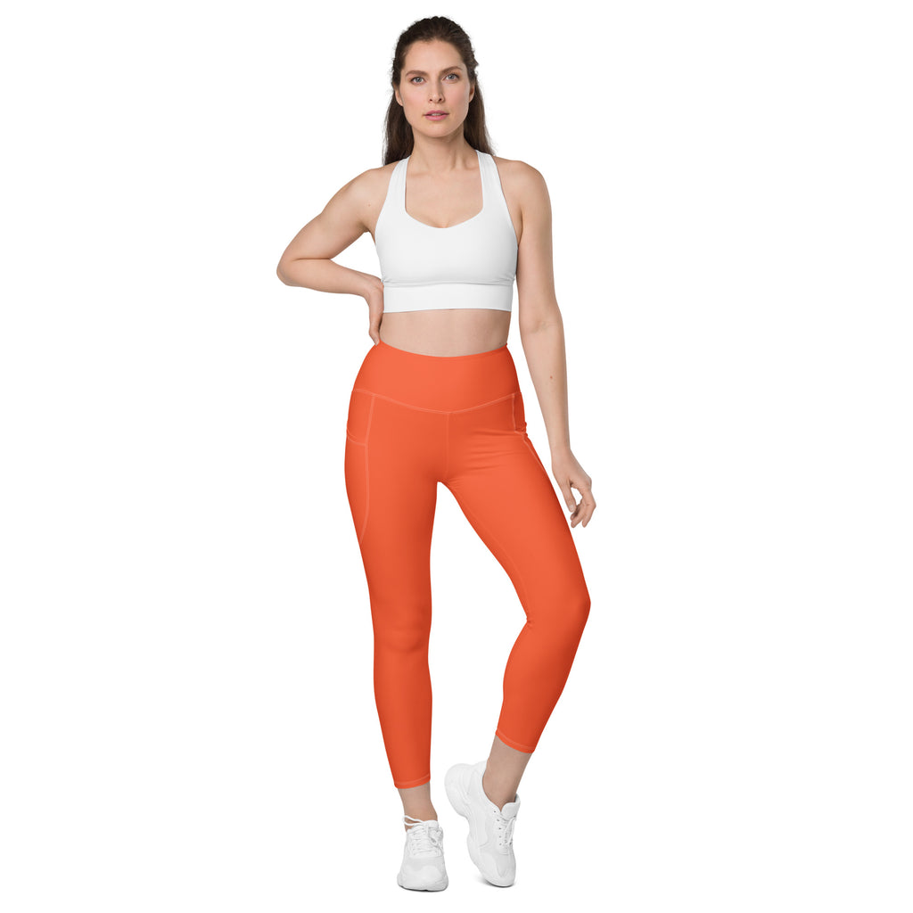Women’s orange high-waisted yoga leggings with pockets featuring sleek form-fitting design and soft compression fabric