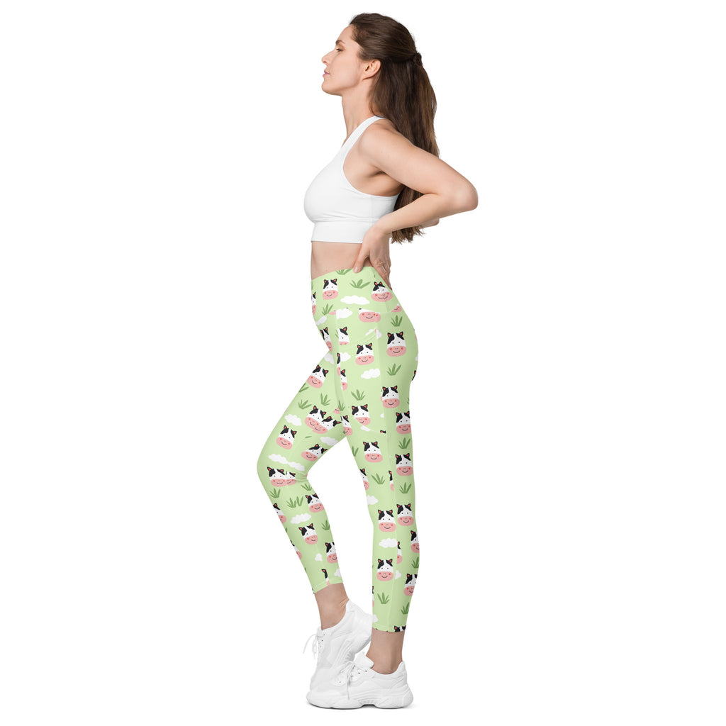 Women’s light green high-waisted cute cow yoga leggings with pockets featuring a playful cow face pattern and grass accents