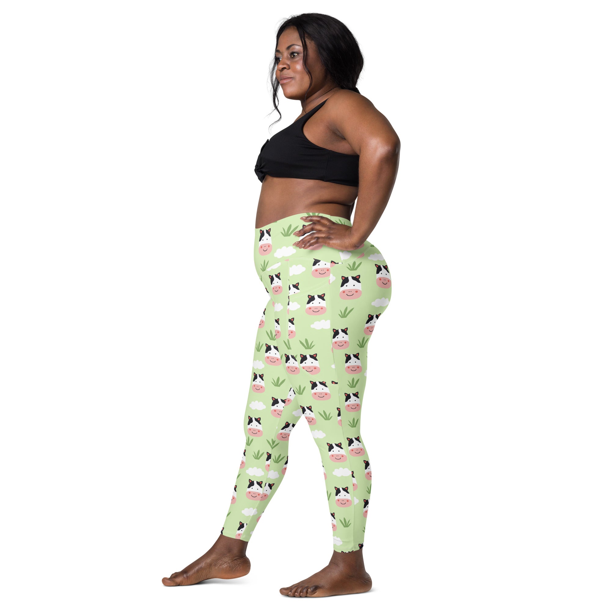 Light green high-waisted women’s cute cow yoga leggings with pockets featuring cartoon cow faces clouds and grass pattern