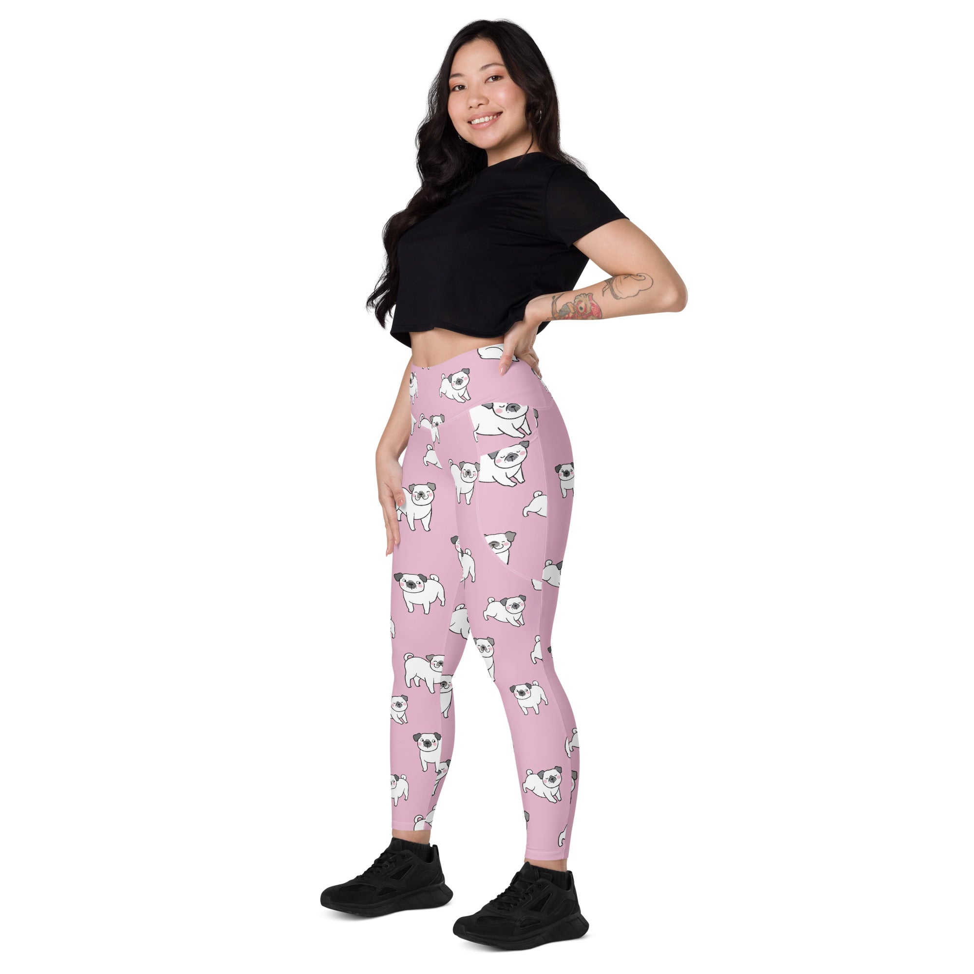 Women’s pink high-waisted yoga leggings with pockets featuring white pug illustrations and soft compression fabric
