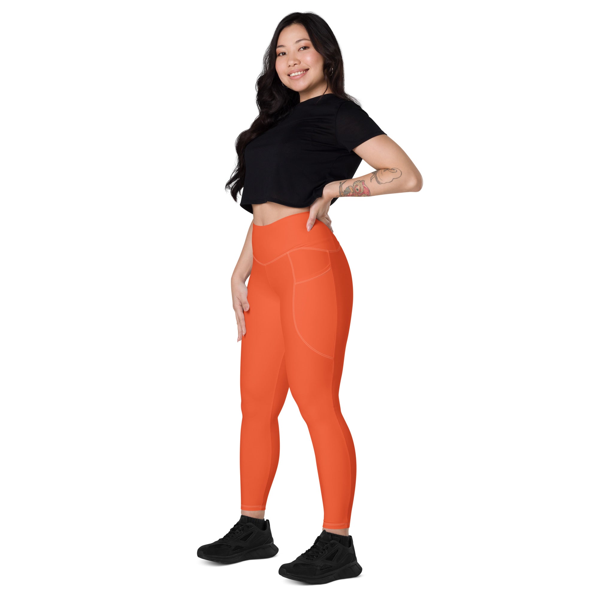 Women’s orange high-waisted yoga leggings with soft compression fabric and subtle side pockets in a sleek design