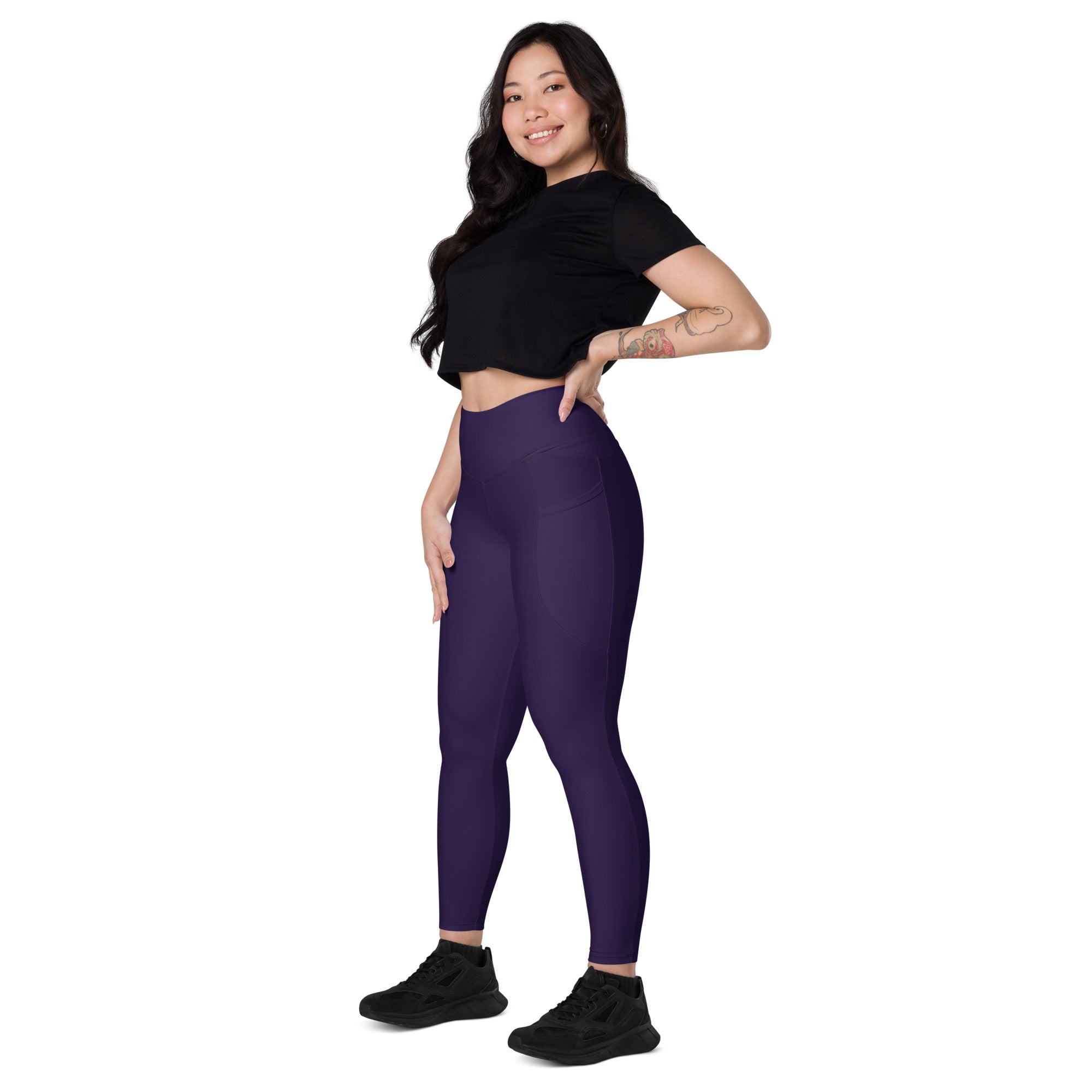 A pair of women’s dark purple high-waisted yoga leggings made from stretchy athletic fabric with pockets