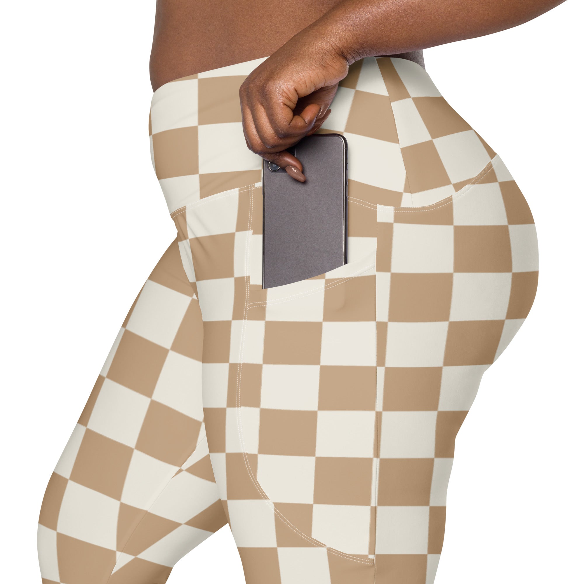 Beige and white checkered high waisted yoga leggings with soft compression and side pocket holding smartphone
