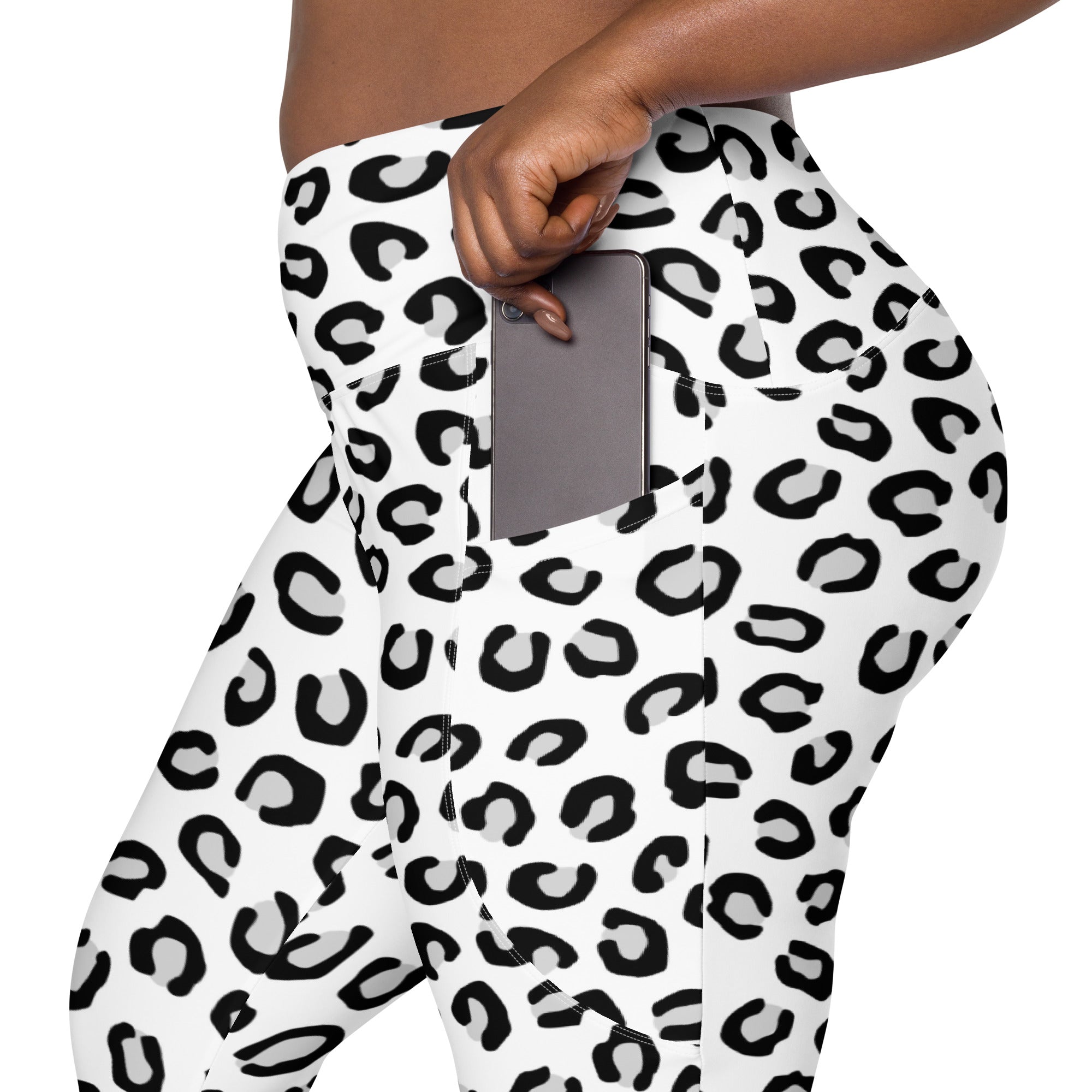 Women’s high-waisted white and black leopard print yoga leggings with soft compression and side pocket holding smartphone