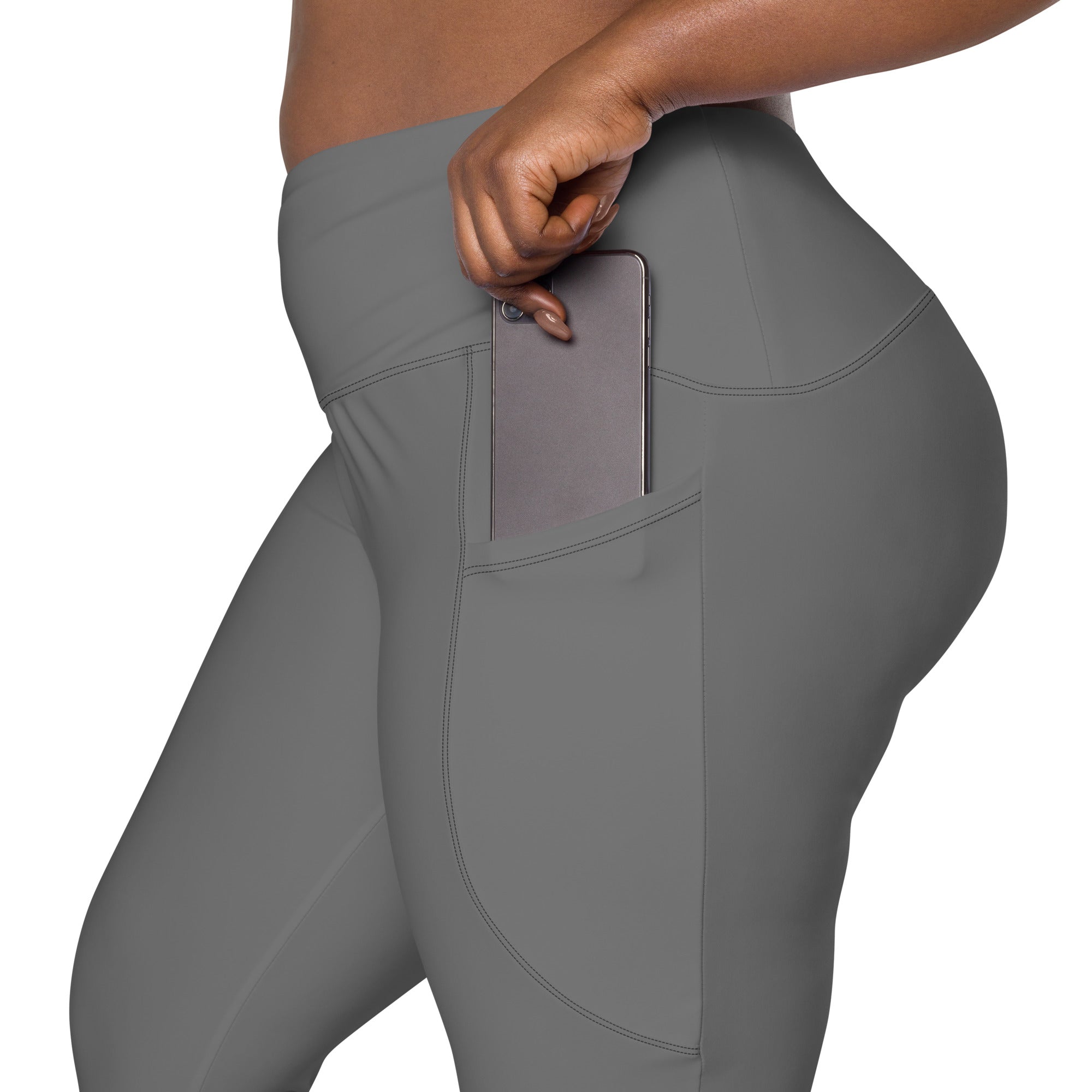 Women’s gray high-waisted yoga leggings with soft compression fabric and side pocket holding a smartphone