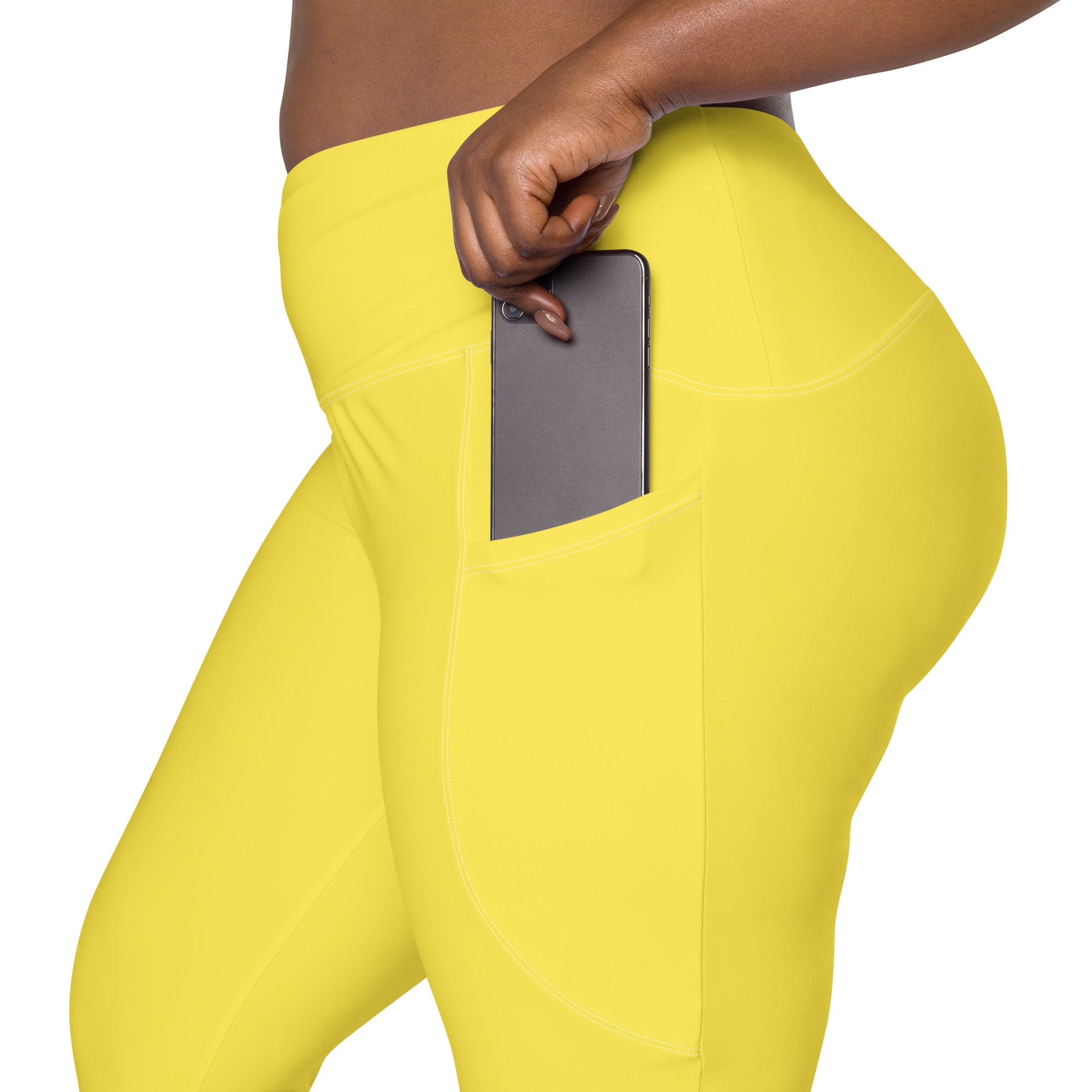 Women’s yellow high-waisted yoga leggings with soft compression and built-in side pocket holding a smartphone