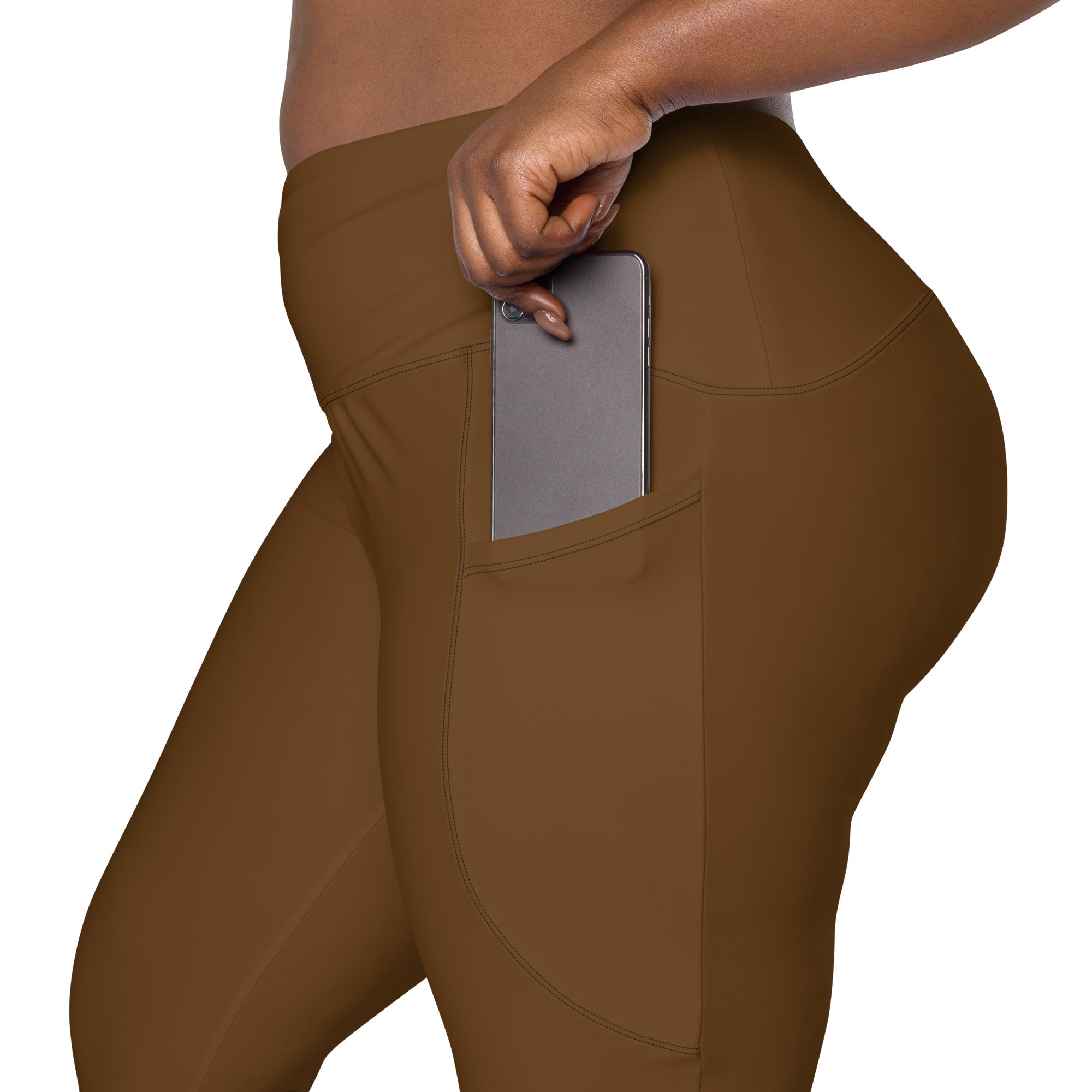 Women’s brown high-waisted yoga leggings with soft compression fabric and side pocket holding a smartphone