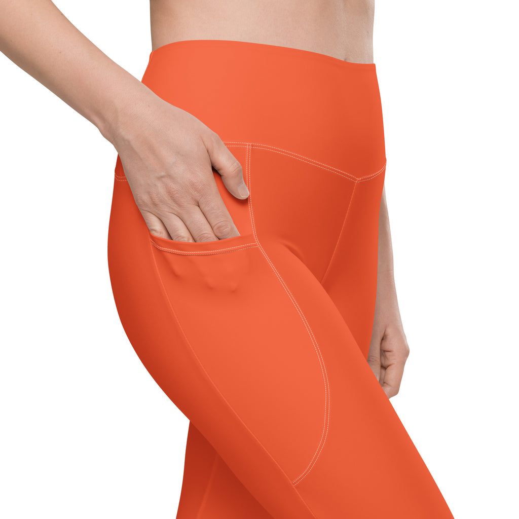Women’s orange high-waisted yoga leggings with pockets made of soft stretchy fabric and subtle white stitching