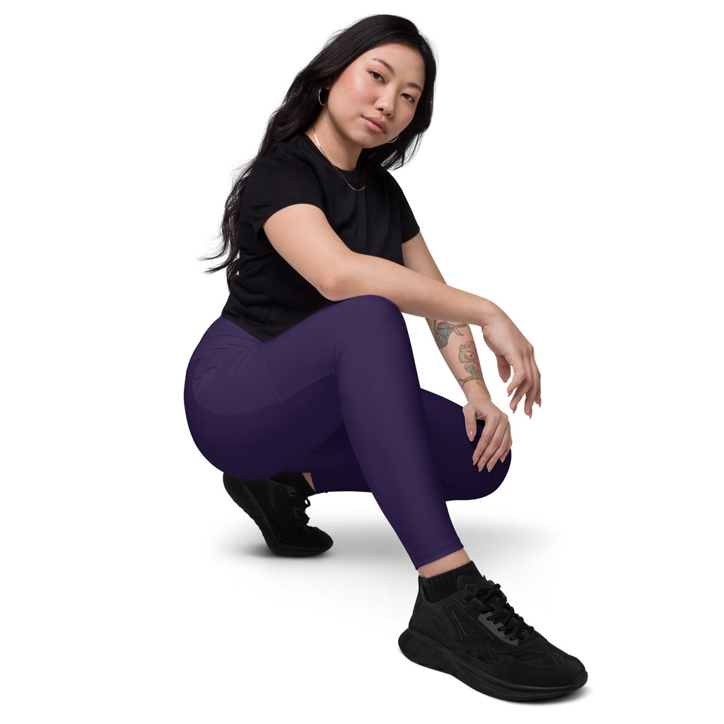 A pair of form-fitting dark purple high-waisted yoga leggings with pockets made of soft compression fabric