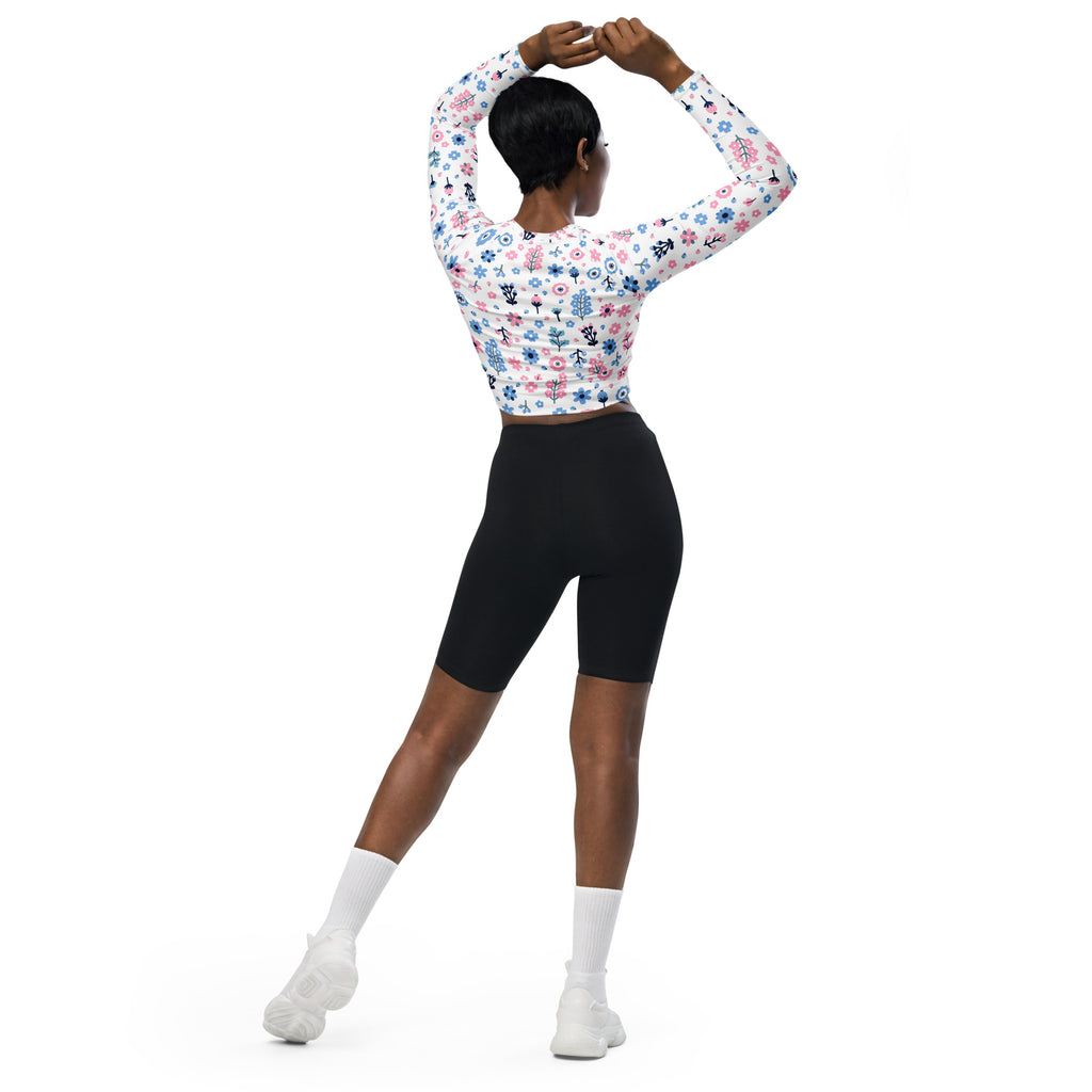 A woman wearing a women’s pastel floral print long sleeve performance crop top with white base and pink blue flowers