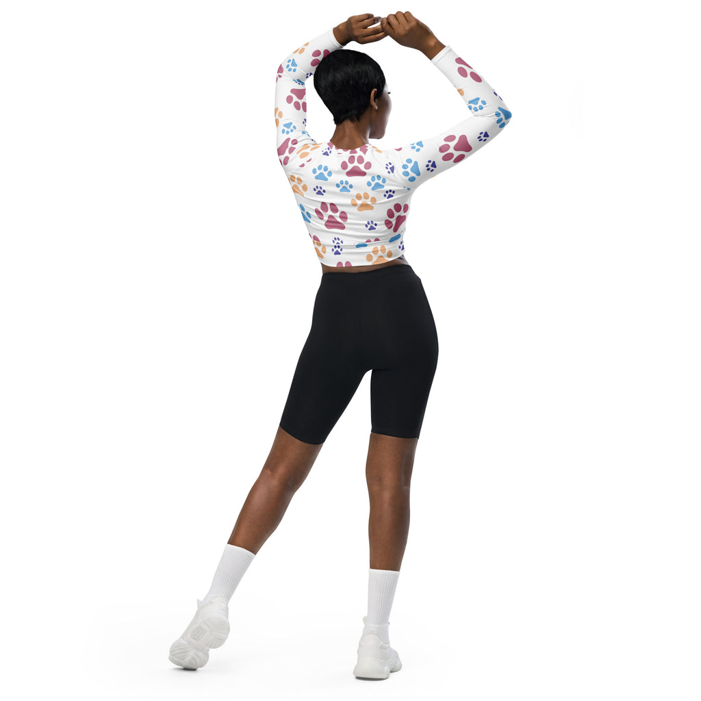 White long-sleeved crop top with colorful paw print pattern designed for women’s performance wear
