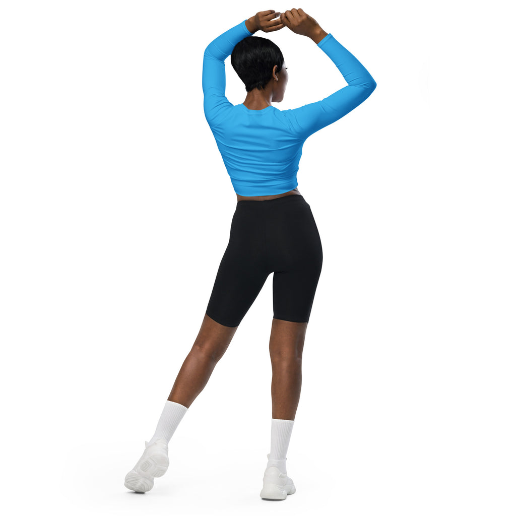 A woman wearing a women’s sky blue long sleeve performance crop top paired with black biker shorts