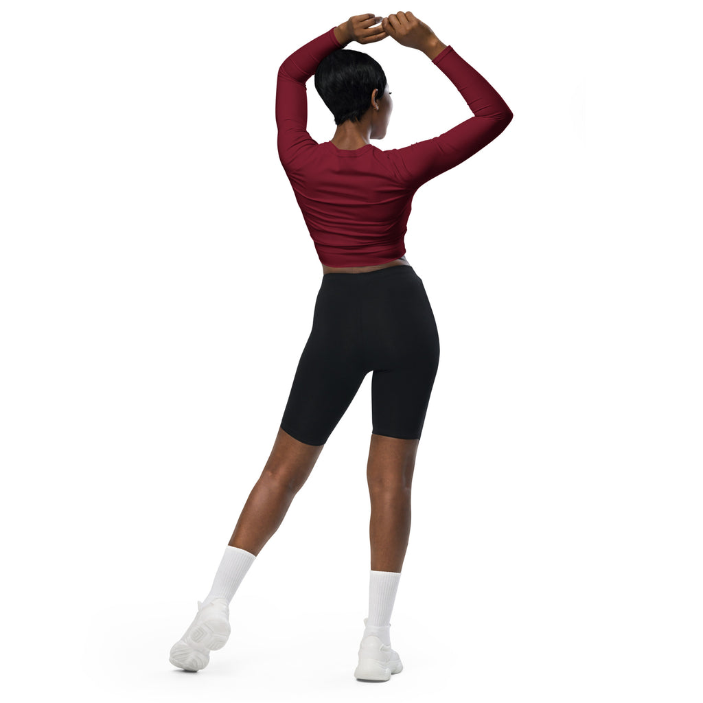 A woman wearing a fitted maroon long sleeve performance crop top with black biker shorts