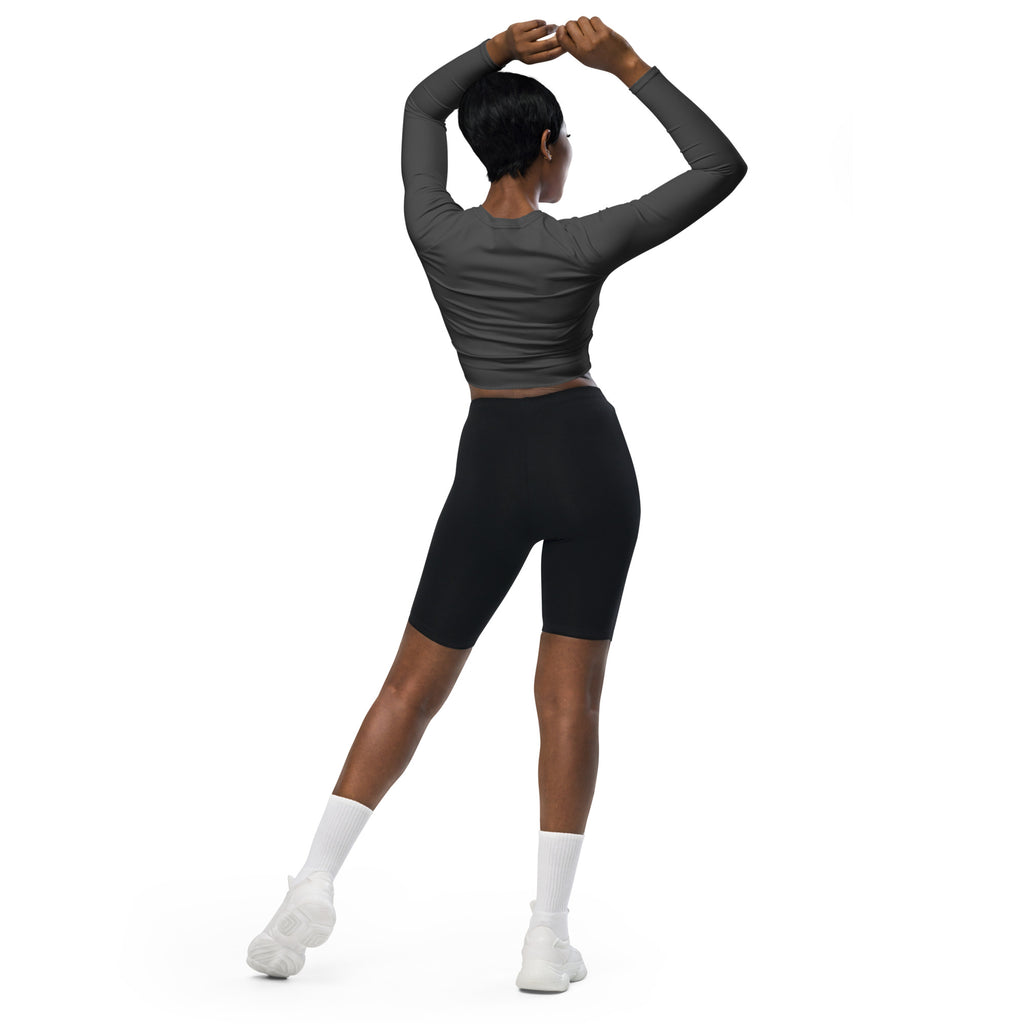 A woman wearing a women’s charcoal long sleeve performance crop top with black biker shorts