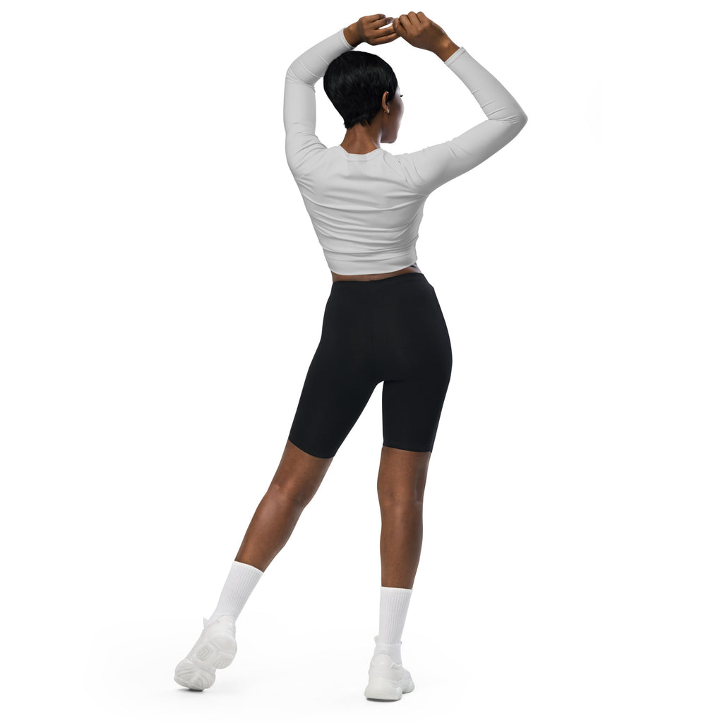 A woman wearing a women’s light gray long sleeve performance crop top paired with black biker shorts