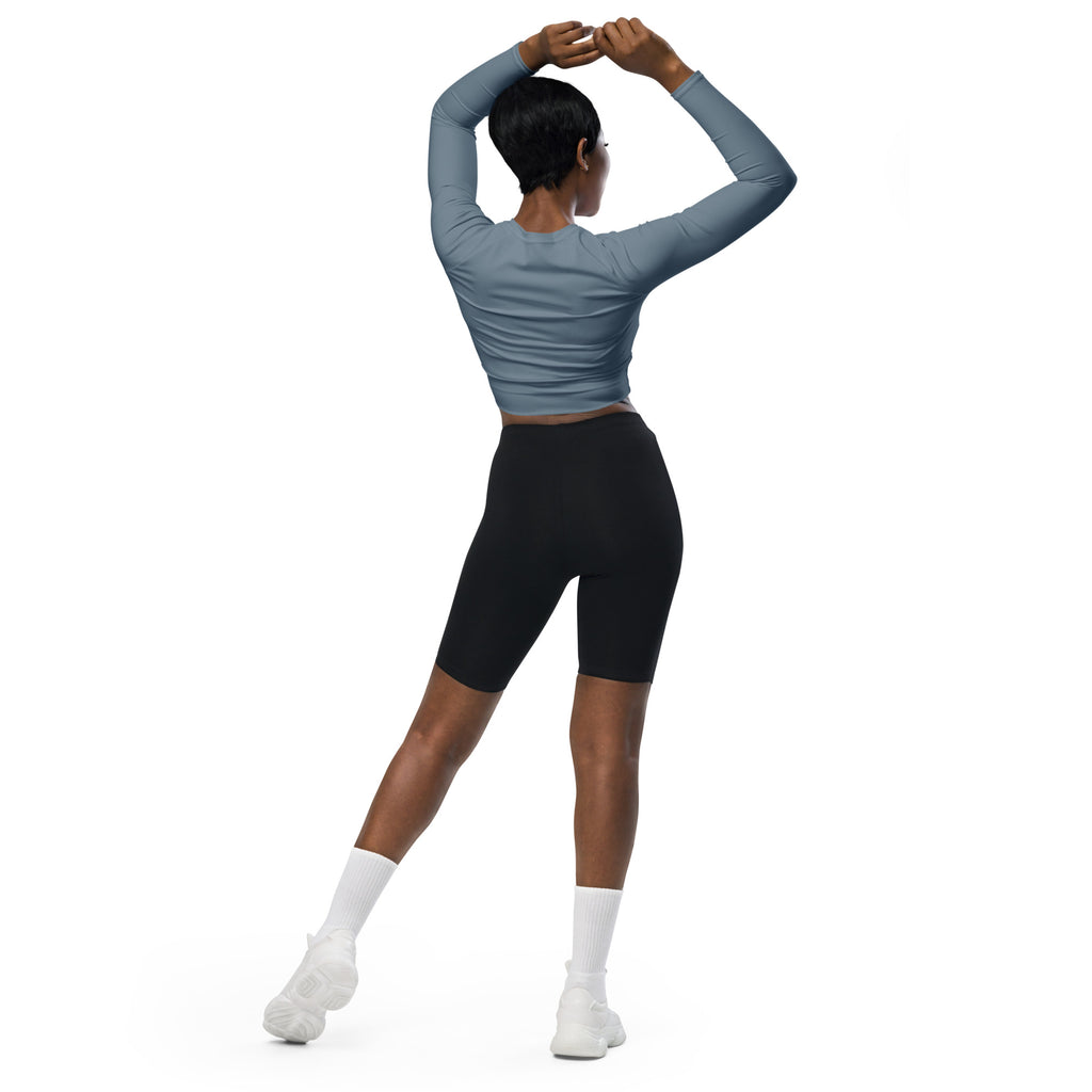 A woman wearing a women’s slate blue long sleeve fitted performance crop top and black biker shorts