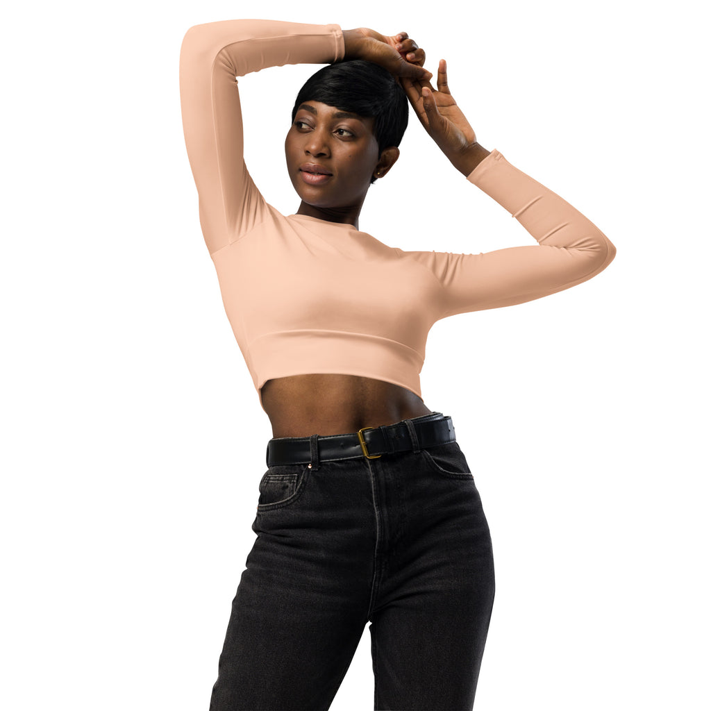 A fitted peach long sleeve performance crop top made of smooth stretchy fabric for women