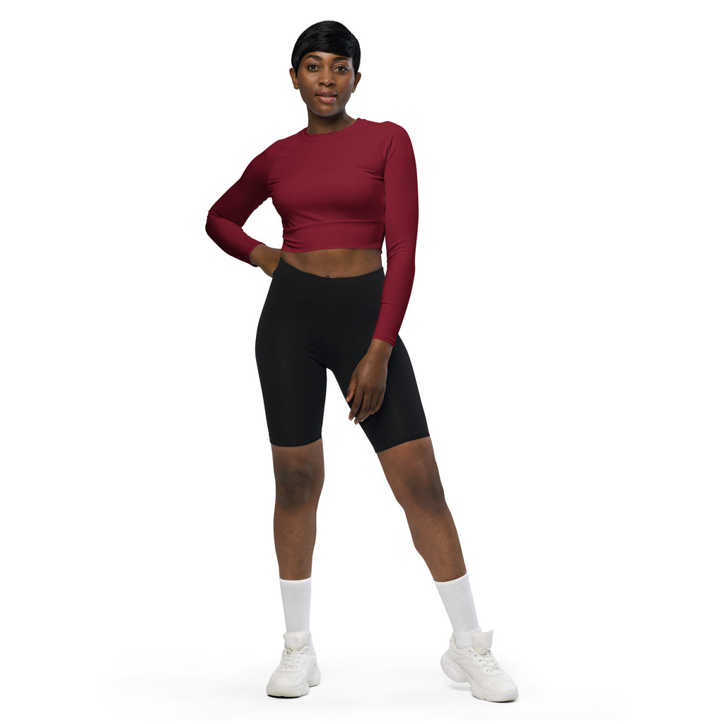 A woman wears a fitted maroon long sleeve performance crop top paired with black biker shorts