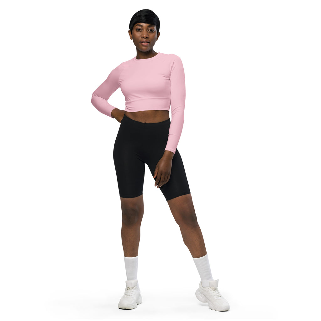 Women’s light pink long sleeve performance crop top paired with black biker shorts and white athletic shoes