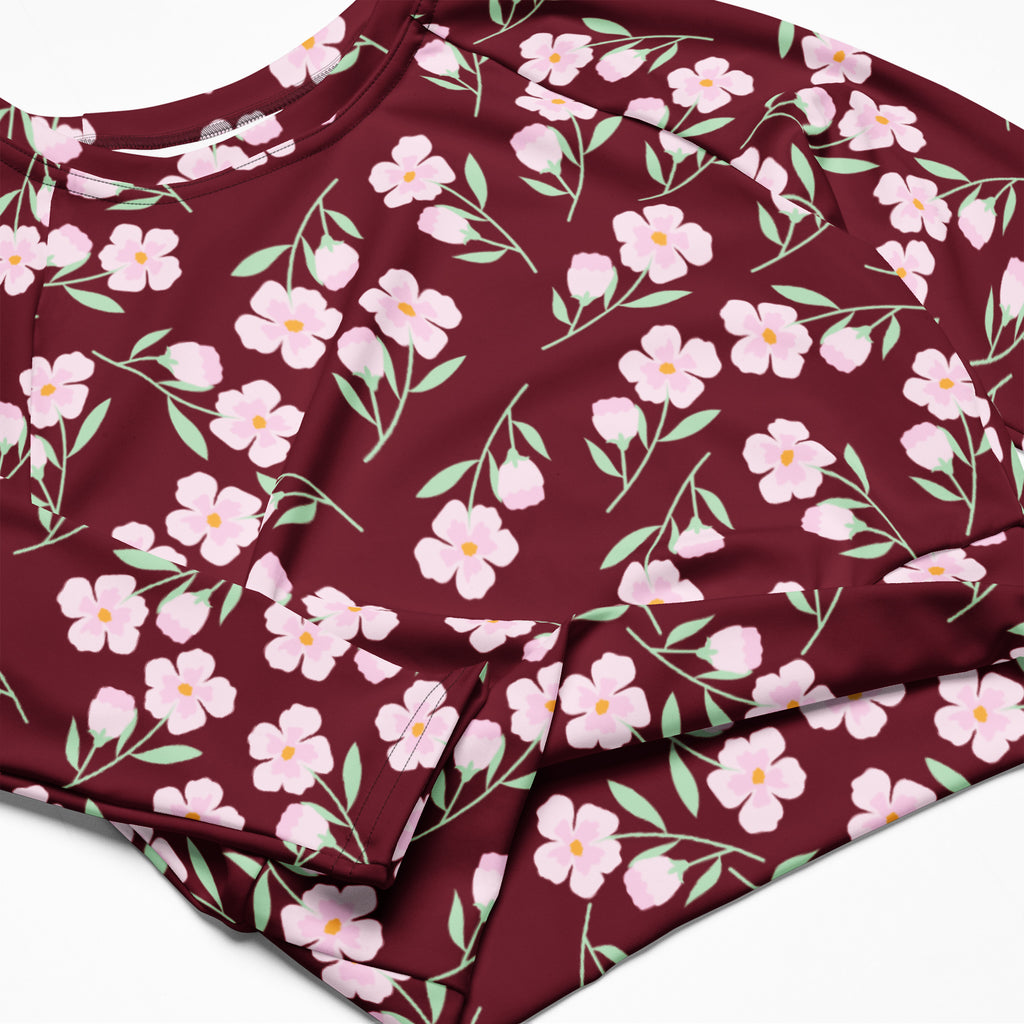 Women’s burgundy long-sleeve performance crop top with delicate pink floral pattern and light green stems