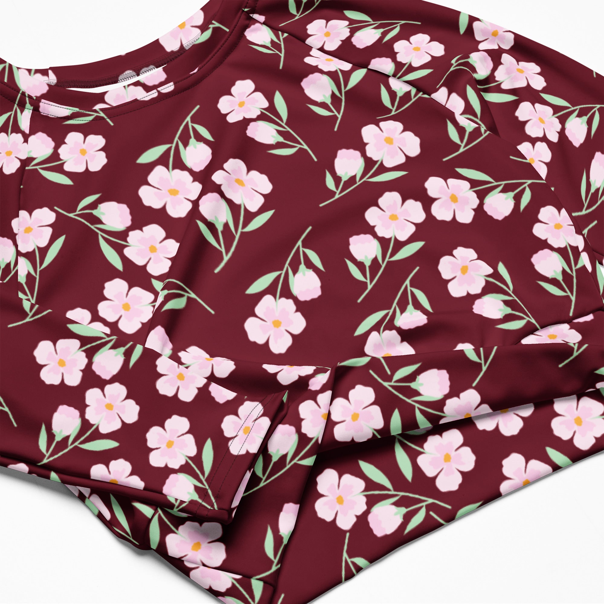 Women’s burgundy long-sleeve performance crop top with delicate pink floral pattern and light green stems