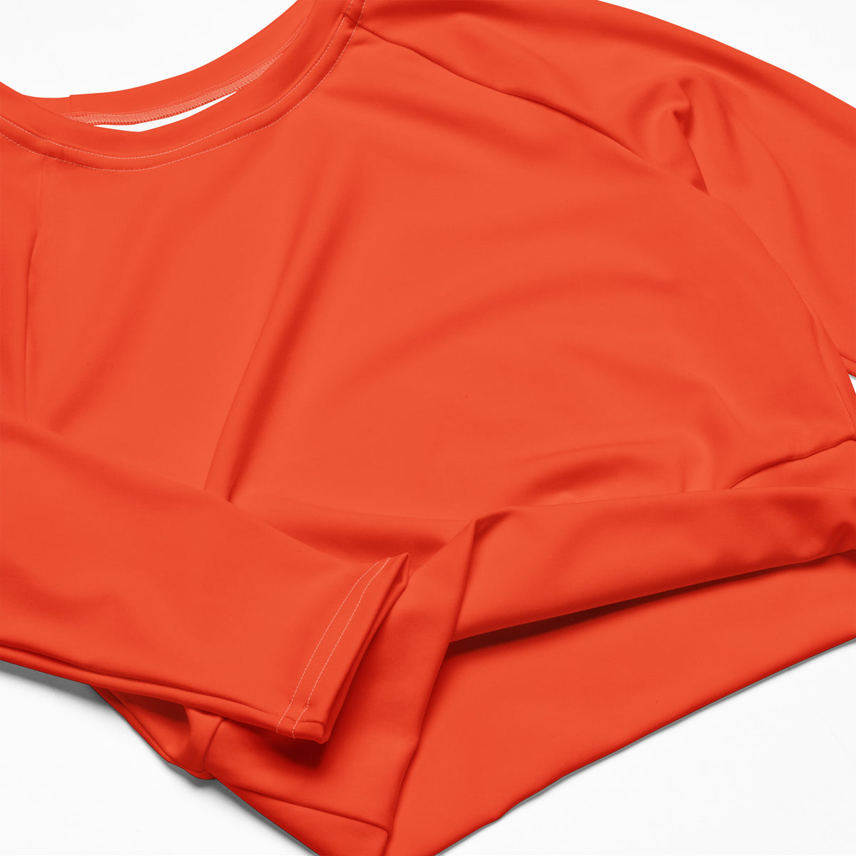 Women’s orange long sleeve performance crop top with smooth stretchy fabric and rounded neckline for athletic use