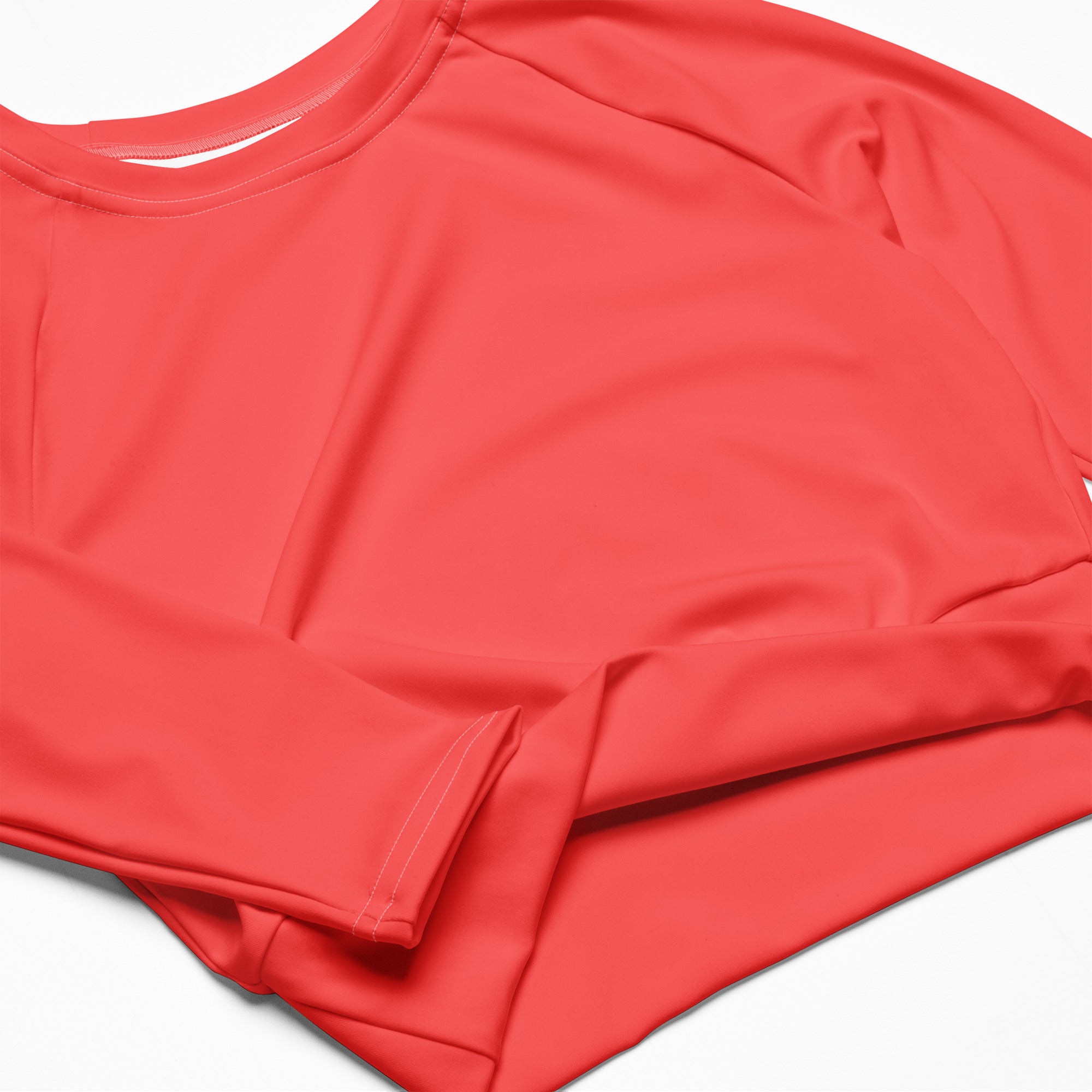 Women’s coral long sleeve performance crop top with smooth stretchy fabric and ribbed cuffs