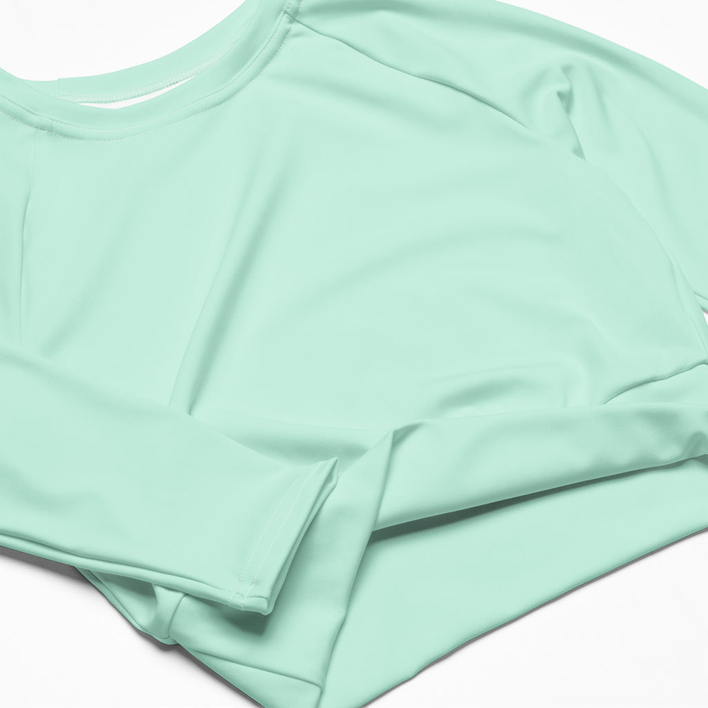 A women’s mint green long sleeve performance crop top with a round neckline and lightweight fabric