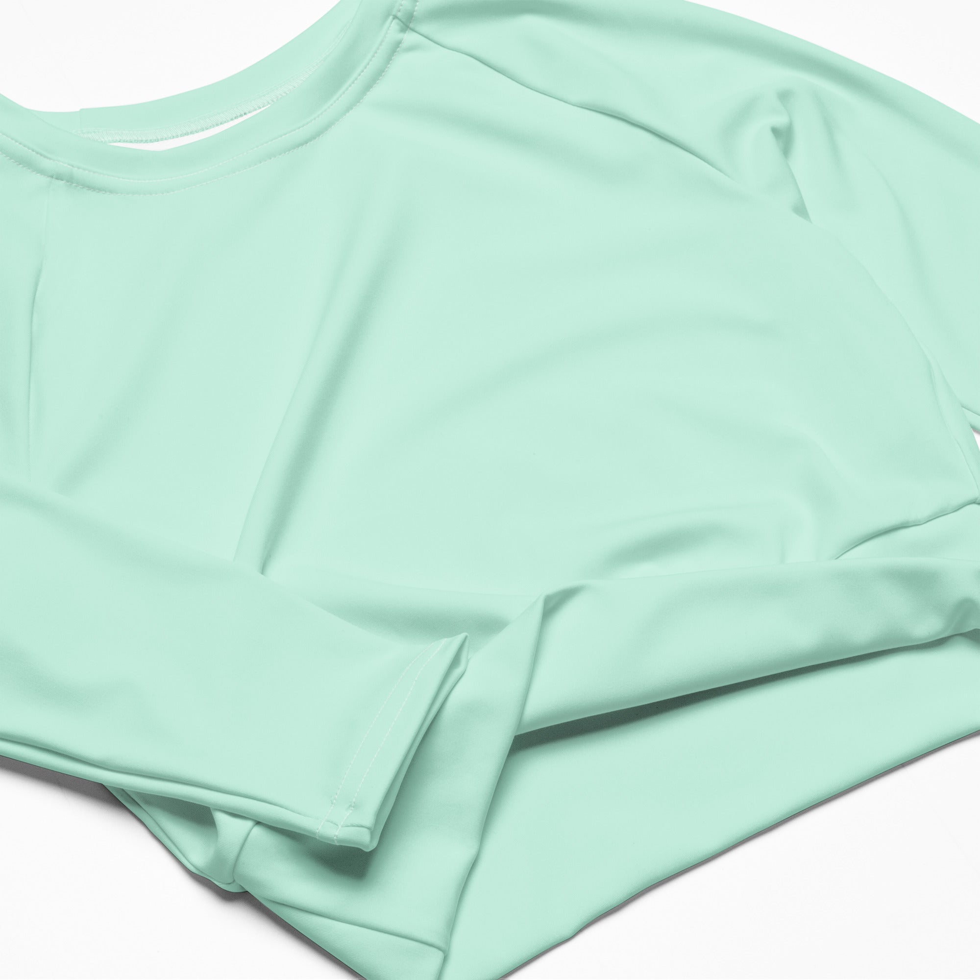 A women’s mint green long sleeve performance crop top with a round neckline and lightweight fabric