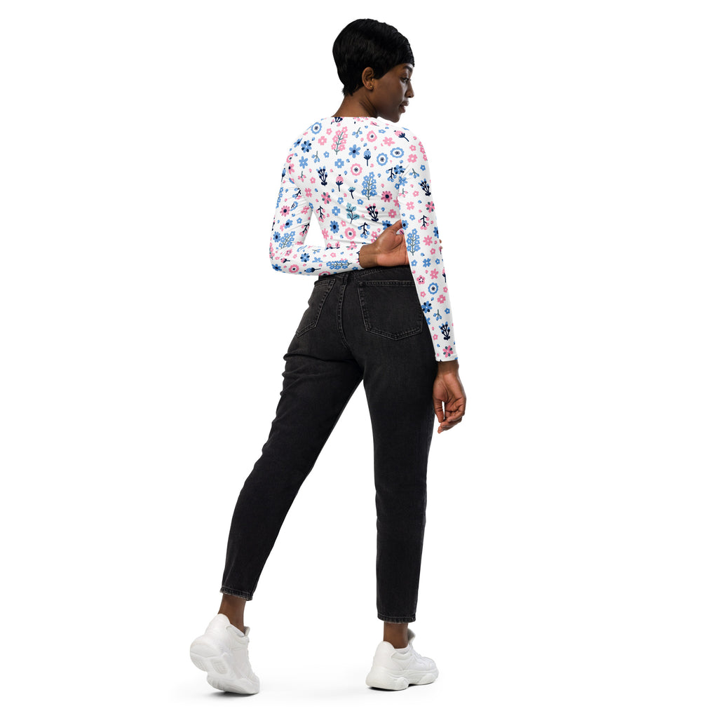 A woman wears a white long sleeve pastel floral print performance crop top with pink and blue flowers