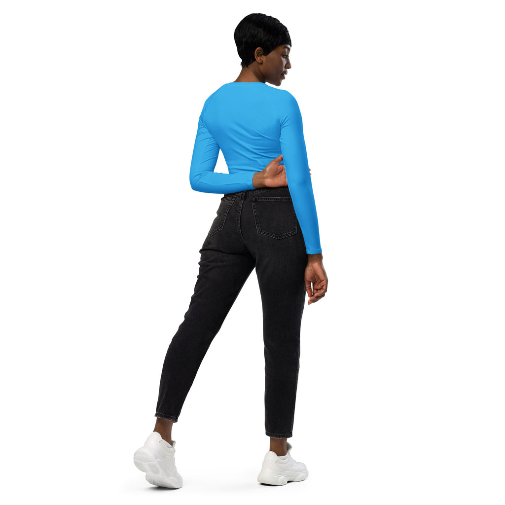 A woman wearing a women’s sky blue long sleeve performance crop top paired with black jeans and white sneakers