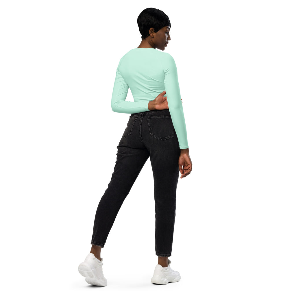 A woman wearing a women’s mint green long sleeve performance crop top paired with black jeans and white sneakers