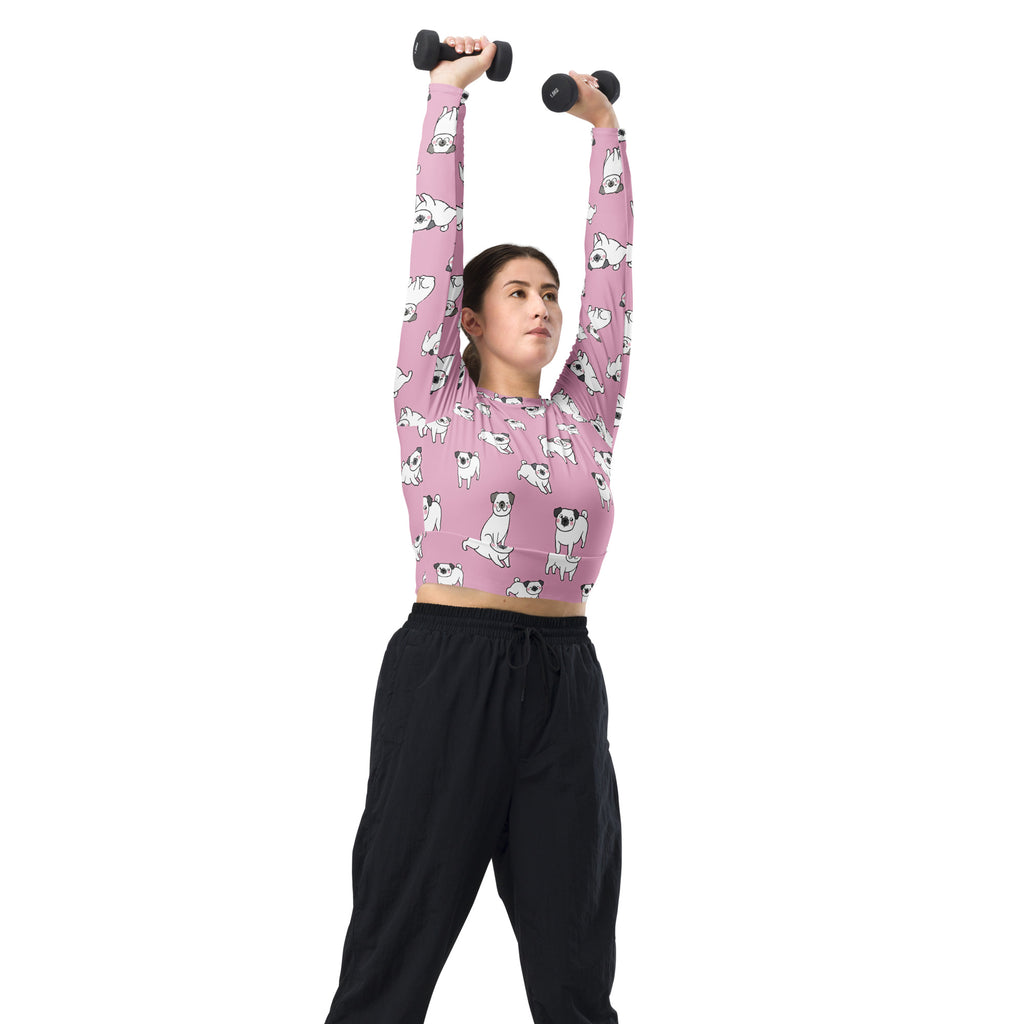 Women’s pink pug long sleeve performance crop top featuring a repeating pattern of white cartoon pugs