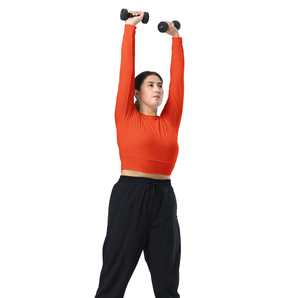 Black dumbbells with textured grips shown alongside a women’s orange long sleeve performance crop top for workouts